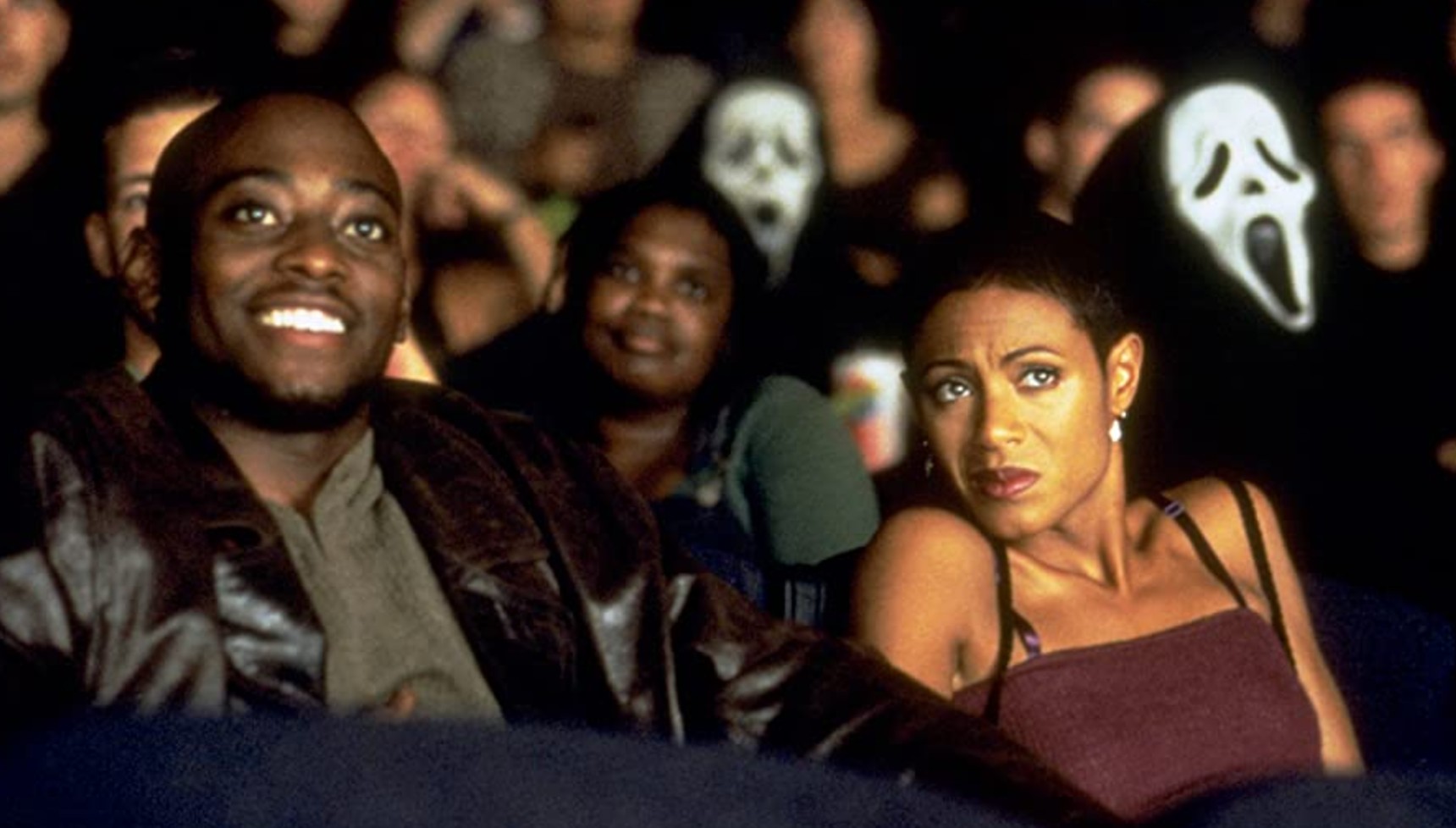 Omar Epps and Jada Pinkett in a theater with people in Ghostface masks in Scream 2