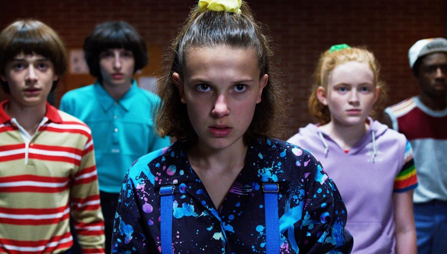 Eleven standing in front of characters in Stranger Things