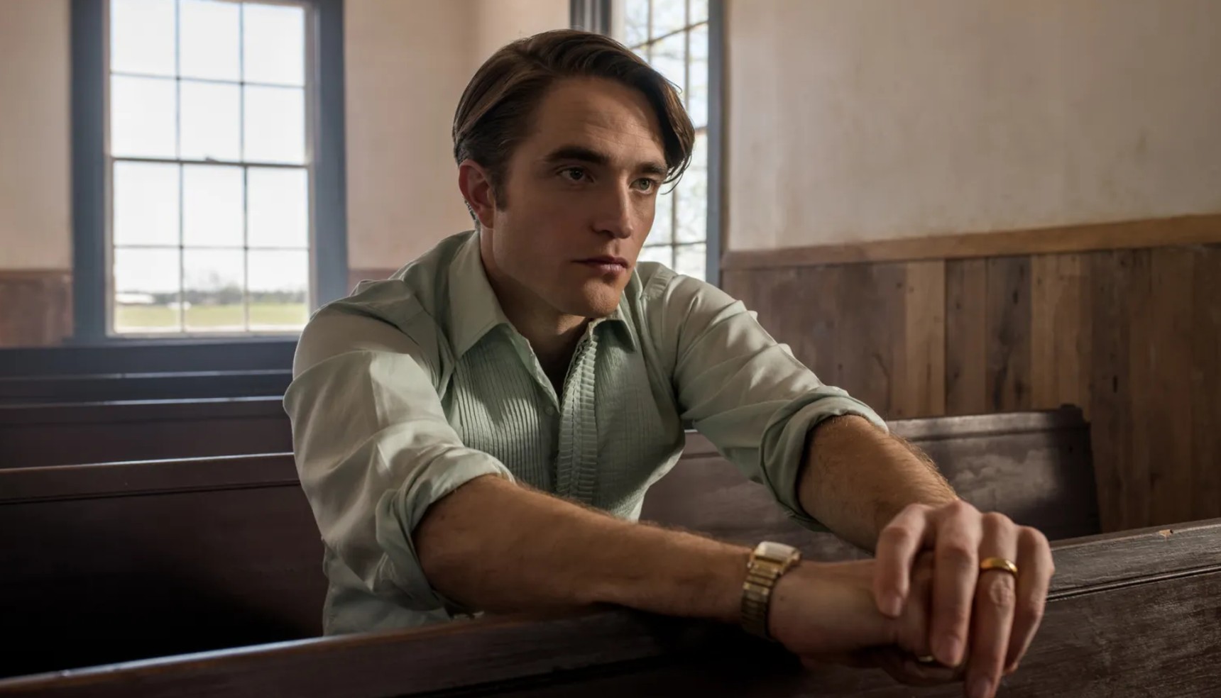 Robert Pattinson sitting in a church pew in The Devil All the Time