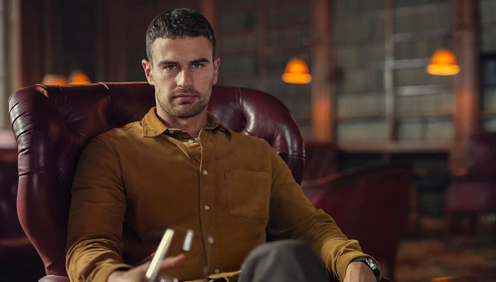 Theo James holding a glass of brandy in The Gentlemen