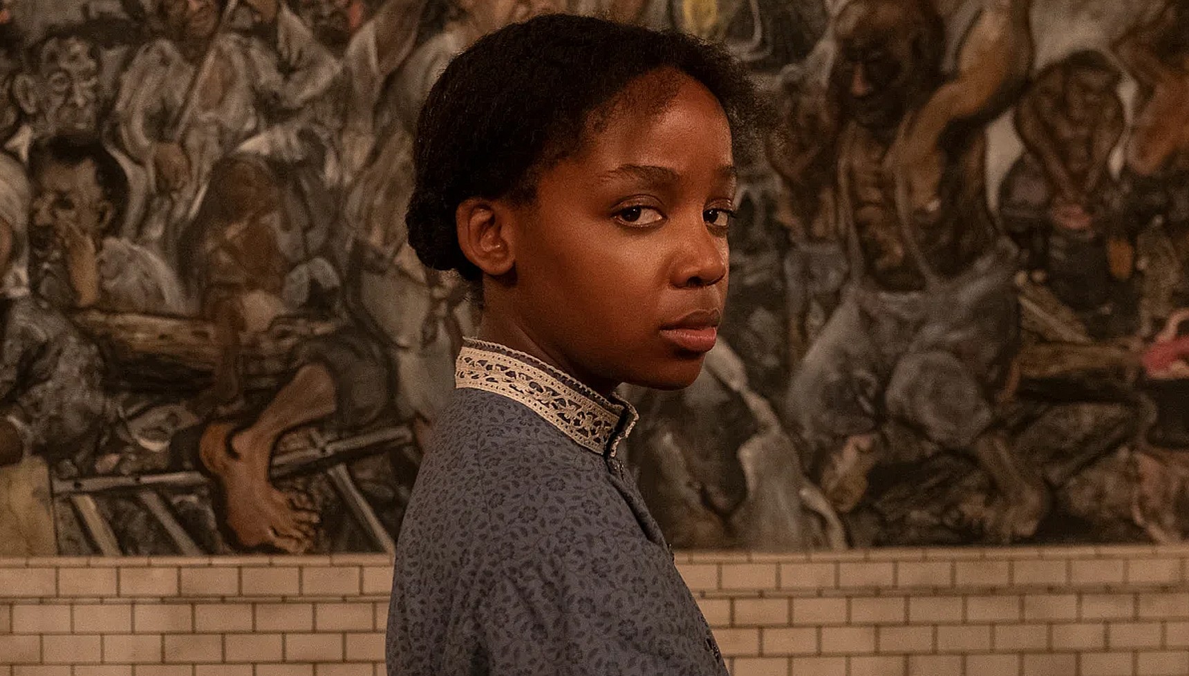 Thuso Mbedu standing in front of a slavery mural in The Underground Railroad