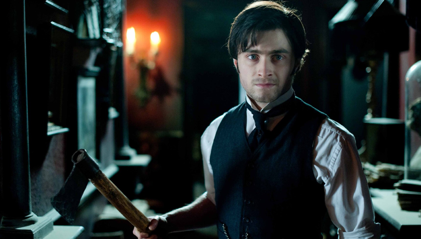 Daniel Radcliffe holding an axe while wearing a waistcoat in The Woman in Black
