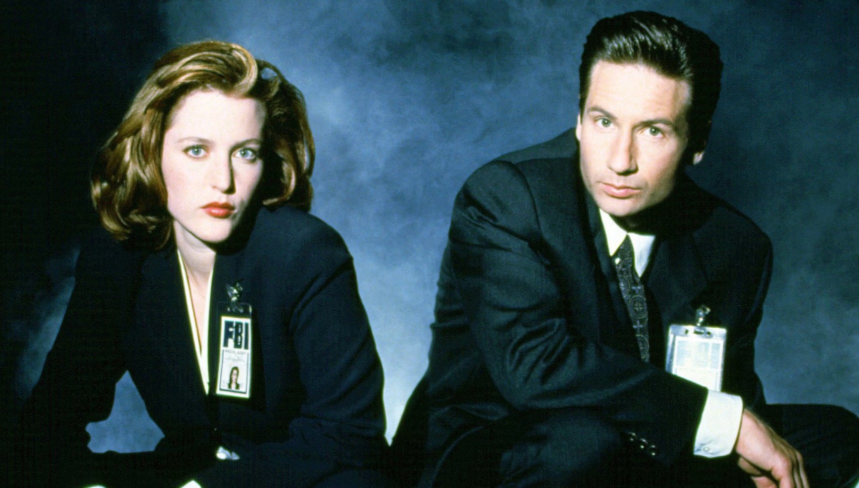 Mulder and Scully kneeling next to each other in a smoky room in The X-Files