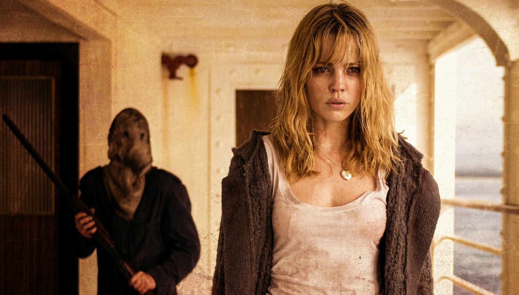 A woman on the balcony of a shop with a masked man behind her