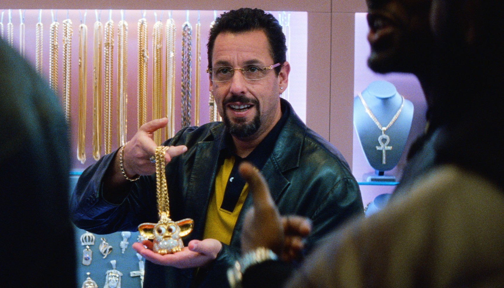 Adam Sandler as Howard Ratner smiling and holding a golden Furby in Uncut Gems