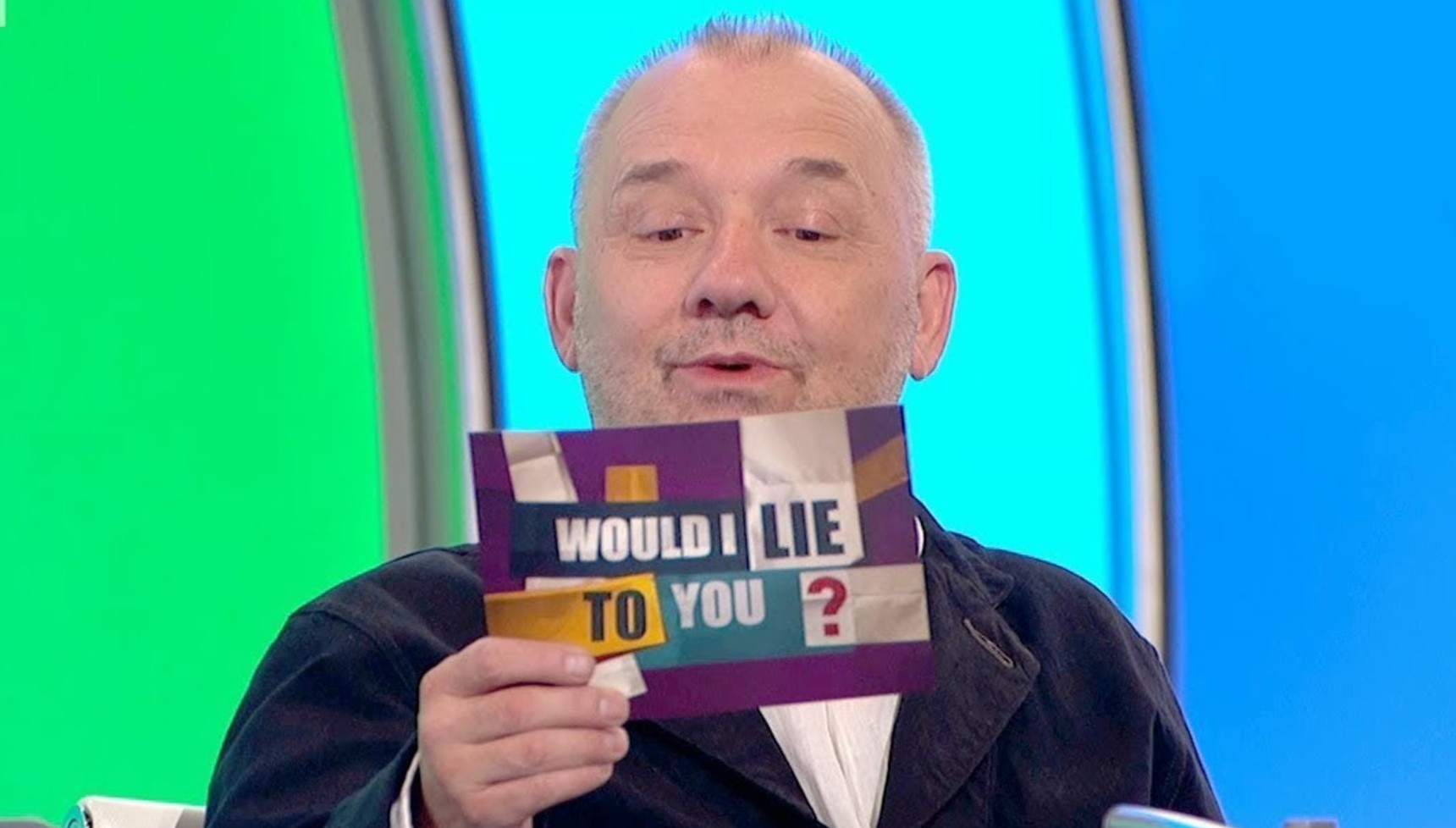 Bob Mortimer holding a Would I Lie To You card 