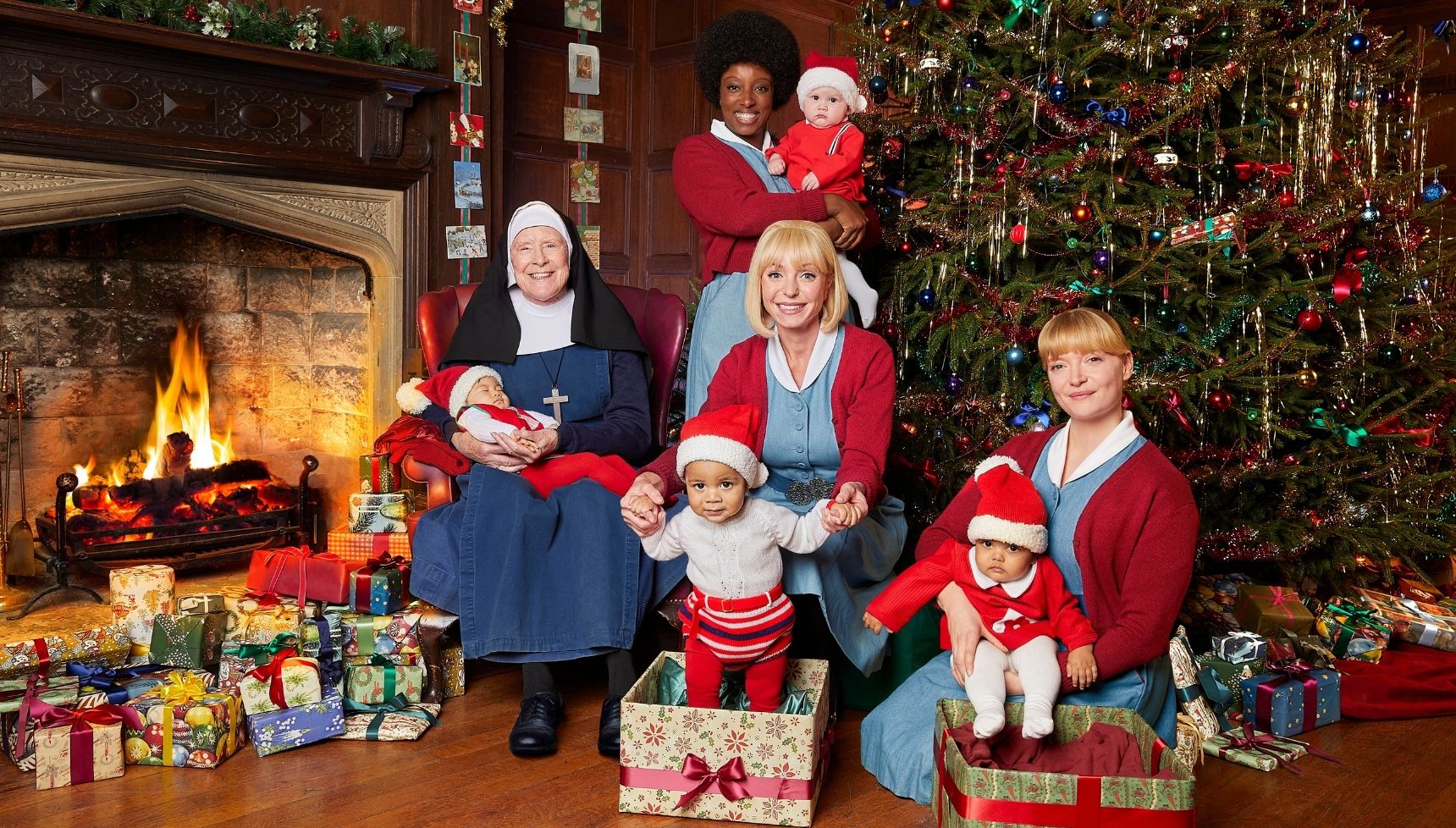 Nonnatus House favourites Sister Monica Joan, Trixie, Joyce and Rosalind all holding babies and standing in front of a Christmas tree for the Call the Midwife Christmas special.
