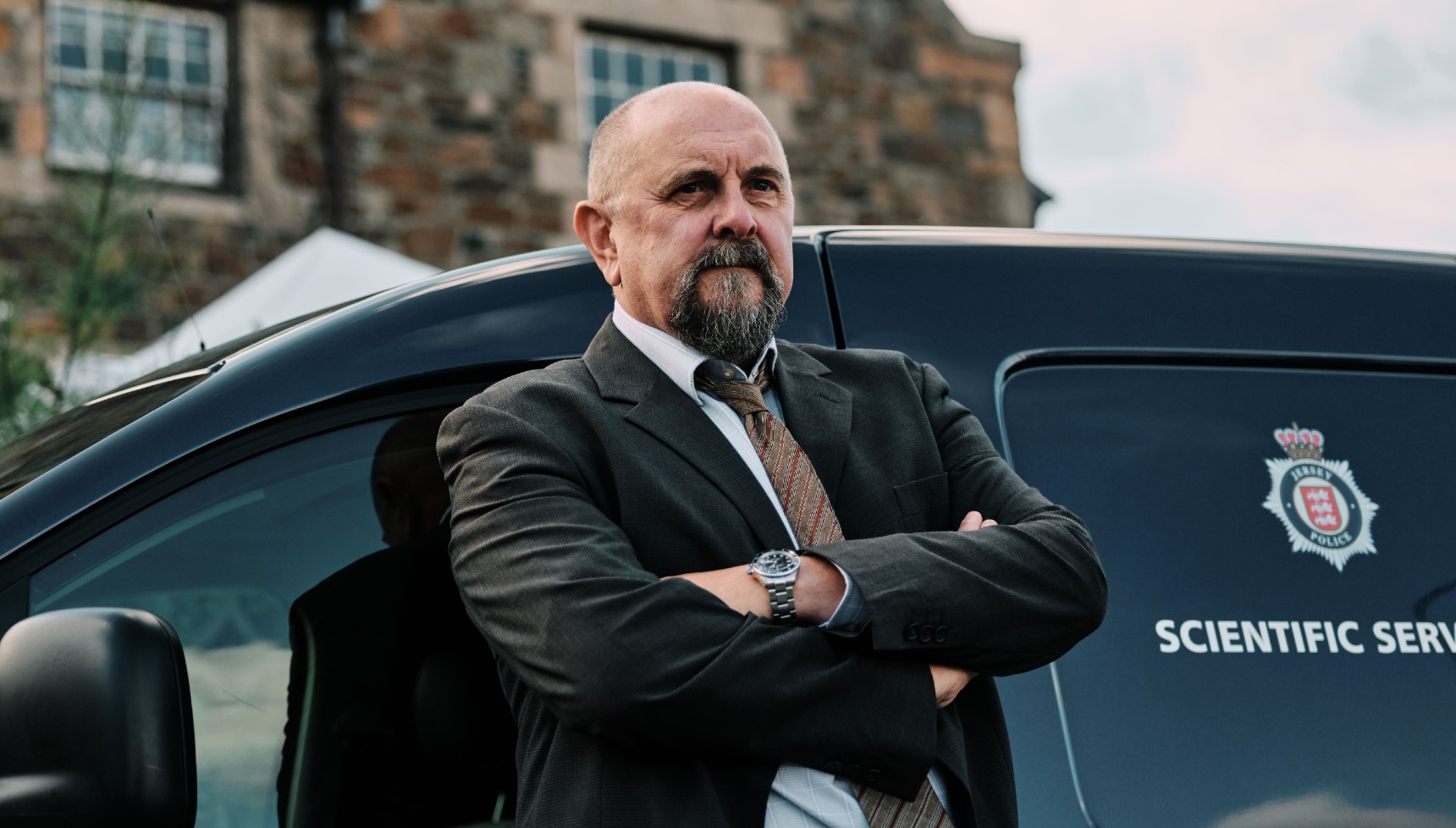 Charles Dale in Bergerac series 2 leaning against a black vehicle with his arms folded