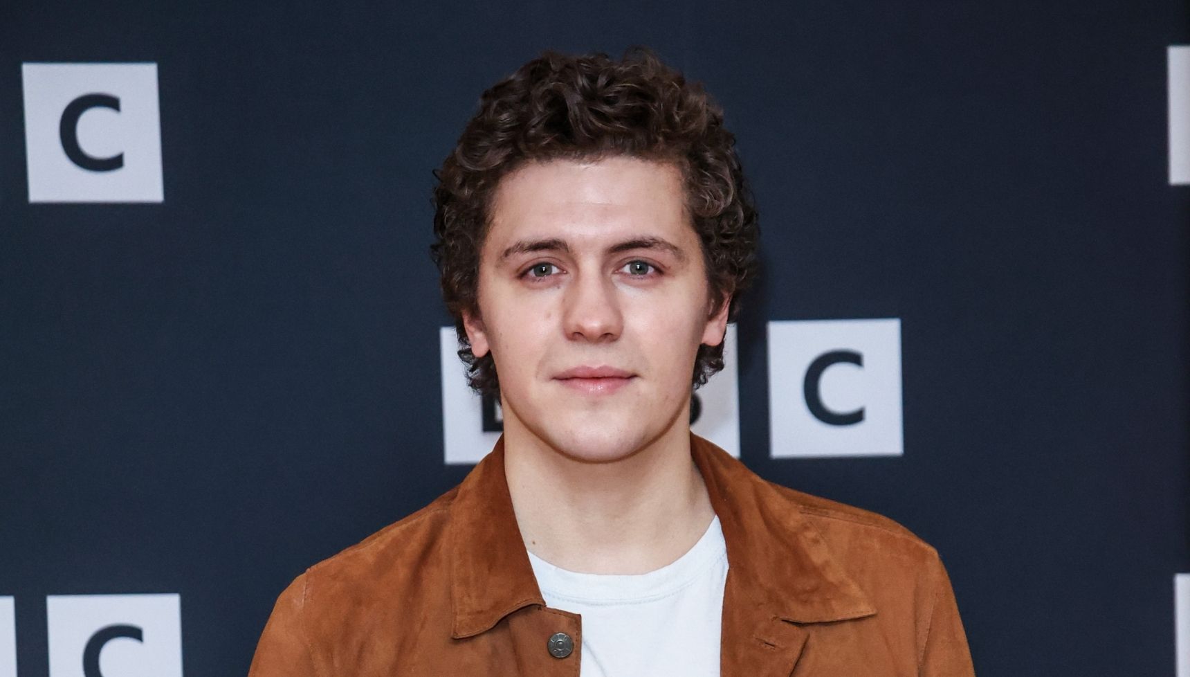 Dylan Llewellyn wears a brown jacket for a BBC premiere