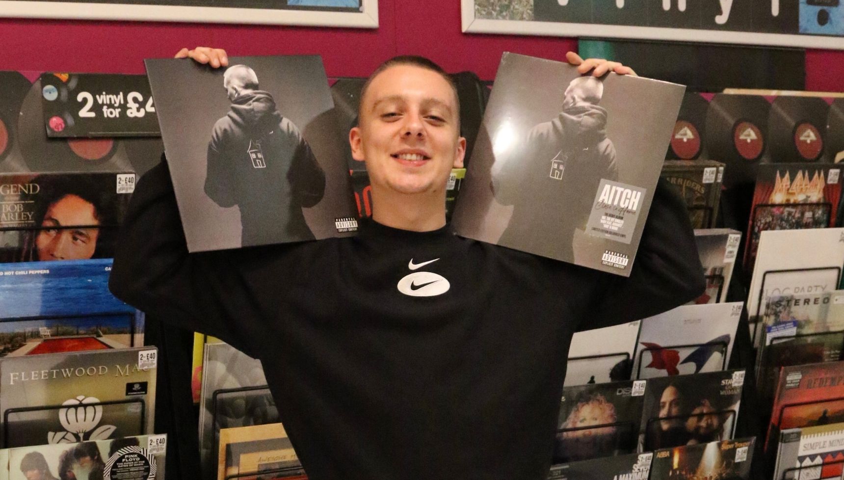 Aitch standing in a record store