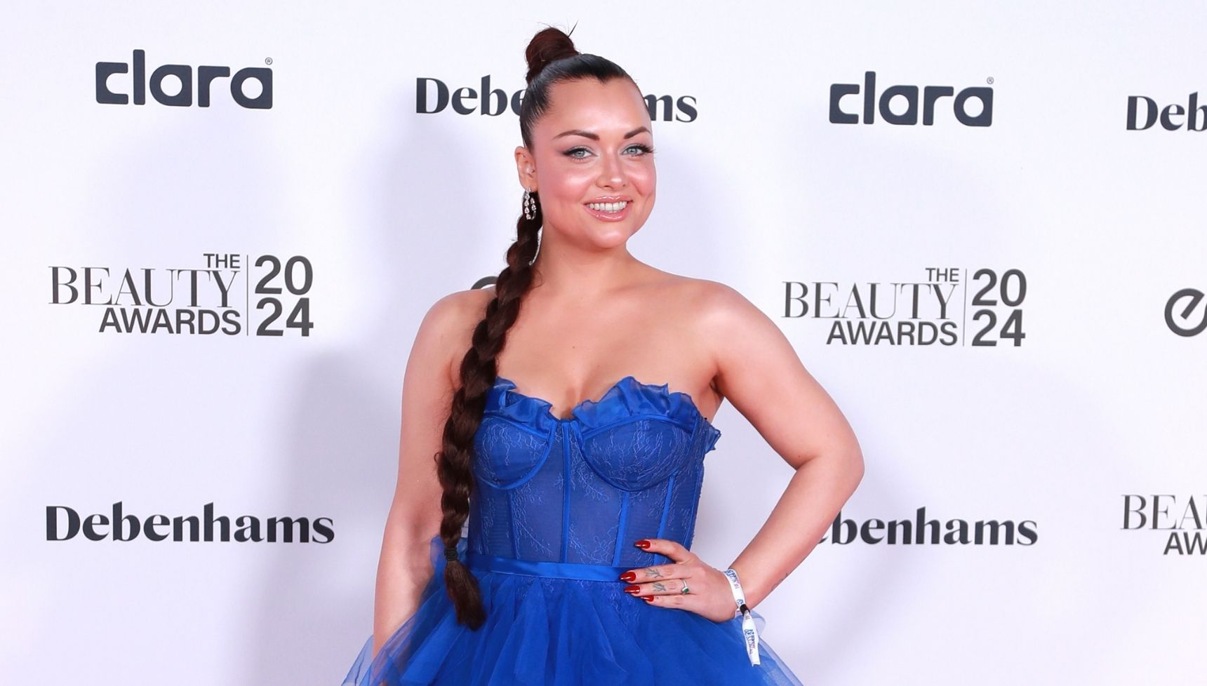 Shona McGarty in a blue strapless gown with her hair in a long plait on the red carpet