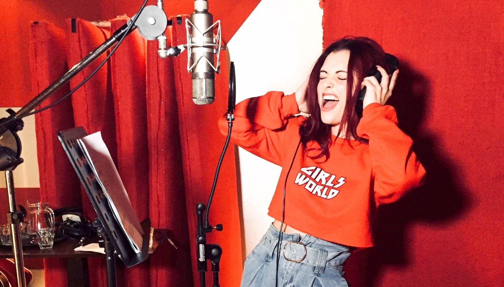 Shona McGarty singing in a recording studio wearing an orange top