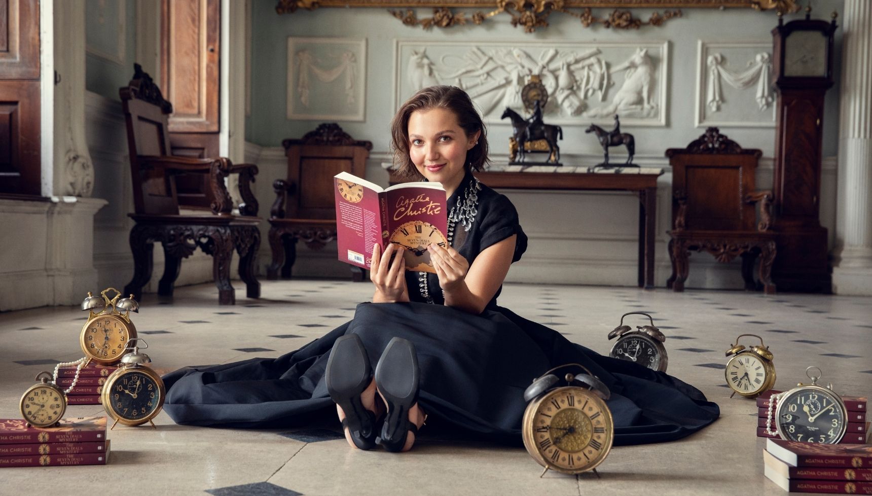 Mia McKenna-Bruce sitting on the floor surrounded by clocks