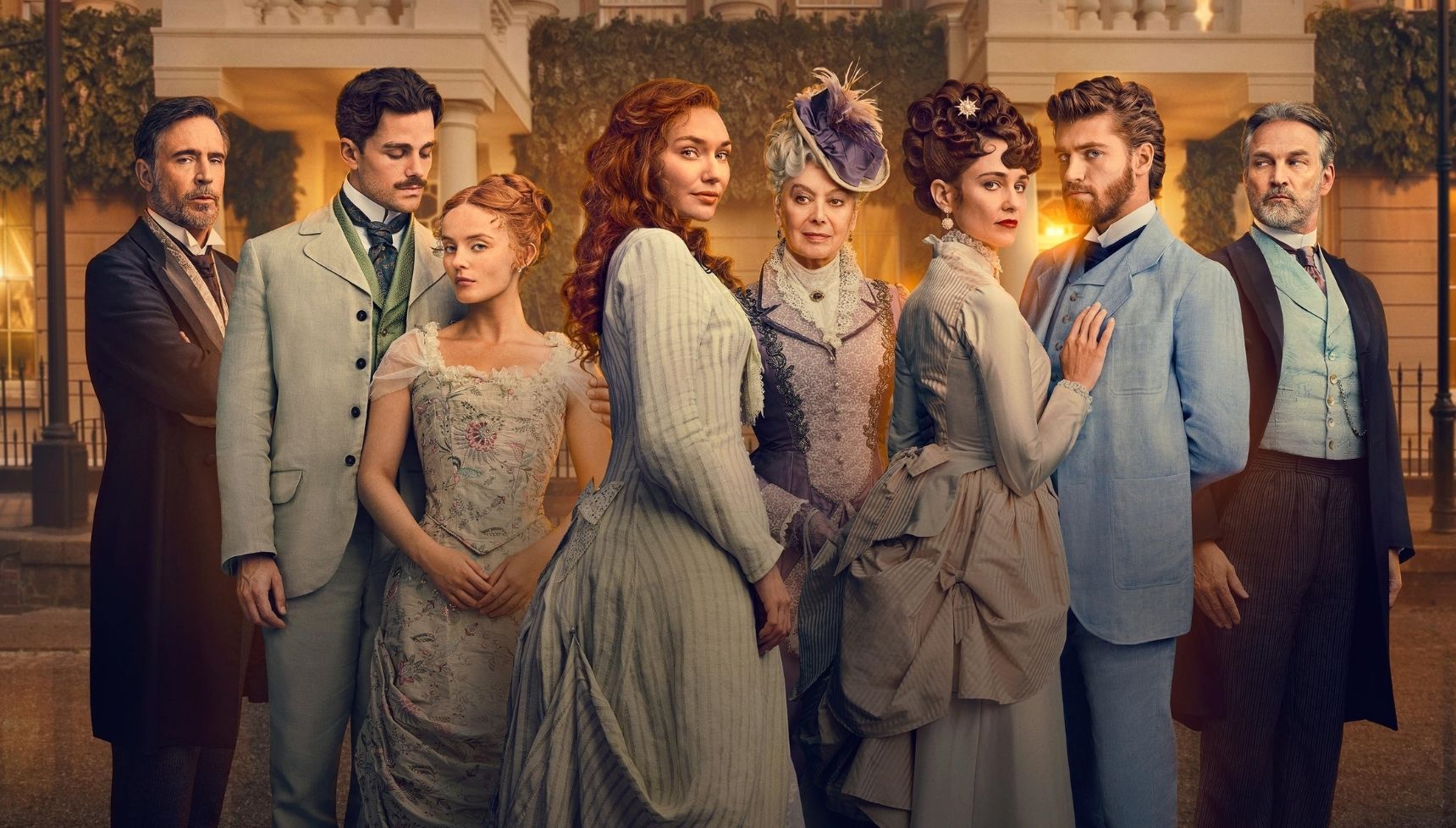 The cast of The Forsytes all in period costumes and standing in front of a smart house.