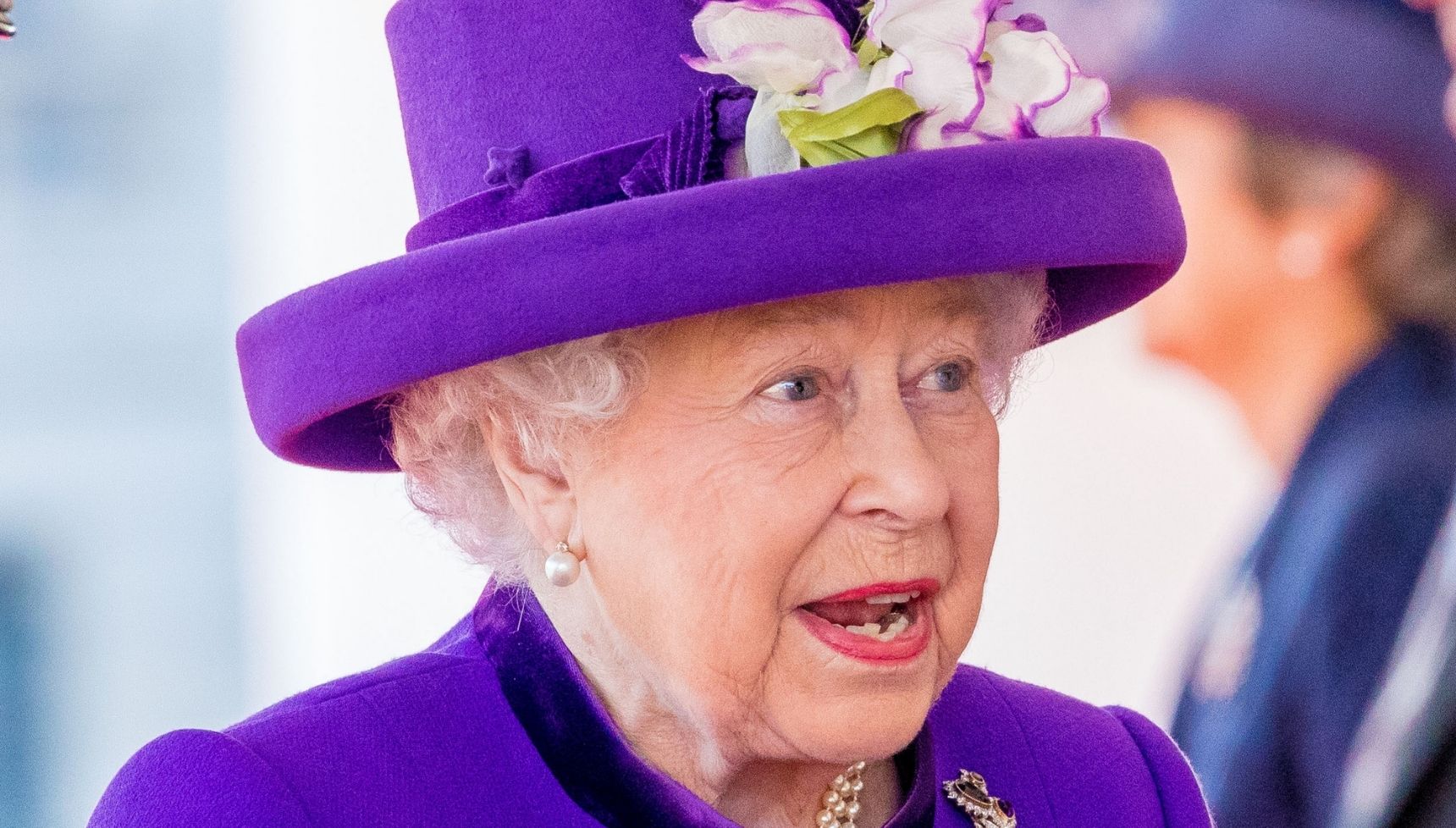 Queen Elizabeth II smiling in purple outfit