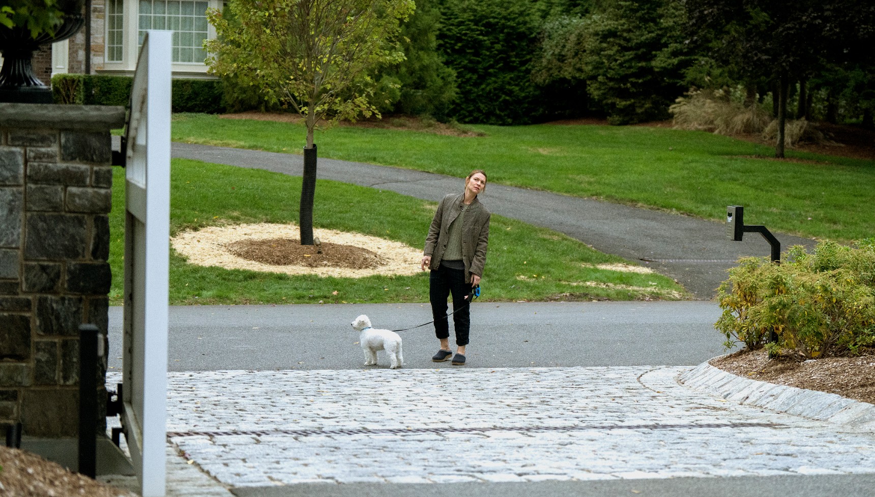 Claire Danes walking her dog at the bottom of a driveway in The Beast in Me