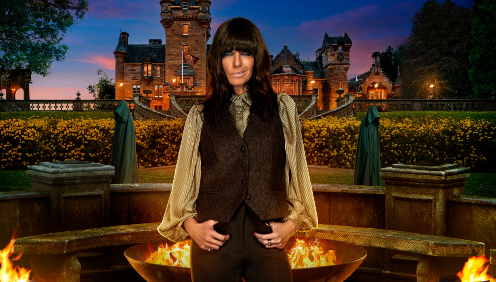 Claudia Winkleman stands before The Traitors castle 
