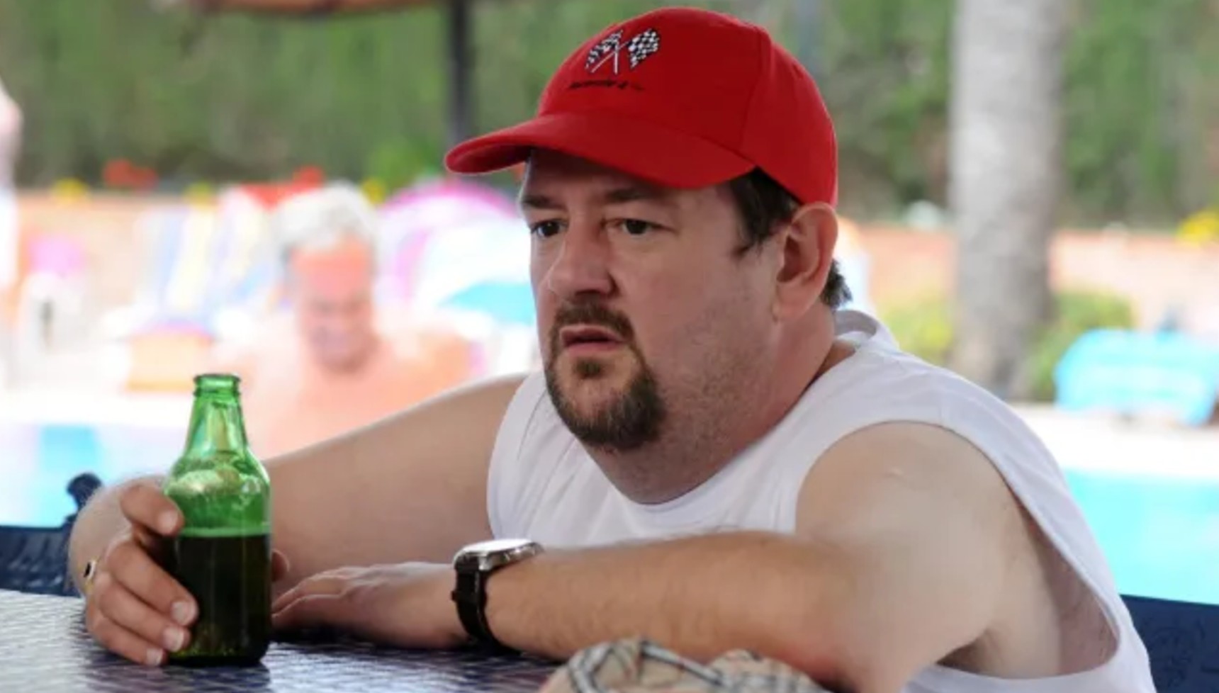 Johnny Vegas sitting at a pool bar with a beer in Benidorm