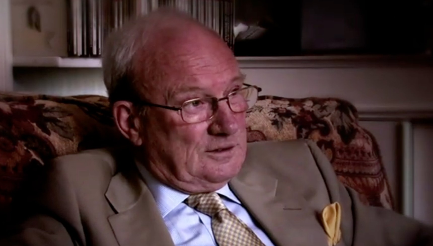 Brian Masters wearing a beige suit in a screenshot from a documentary