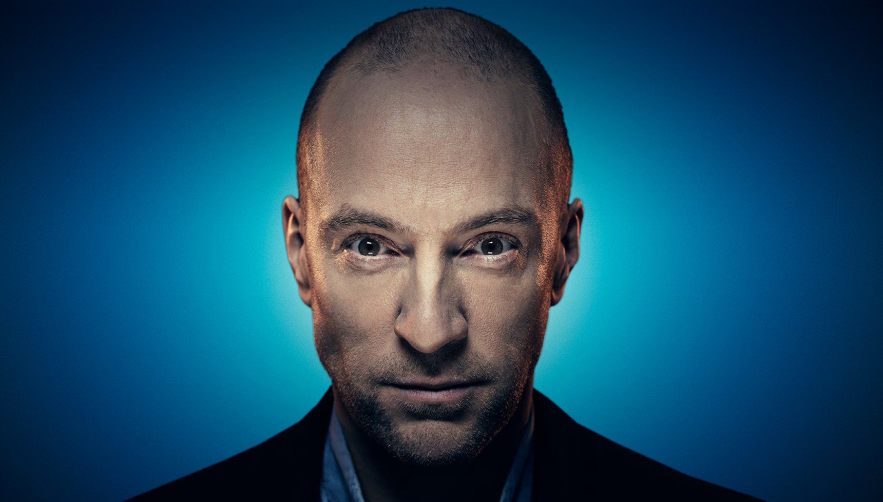 Derren Brown staring at you against a blue backdrop