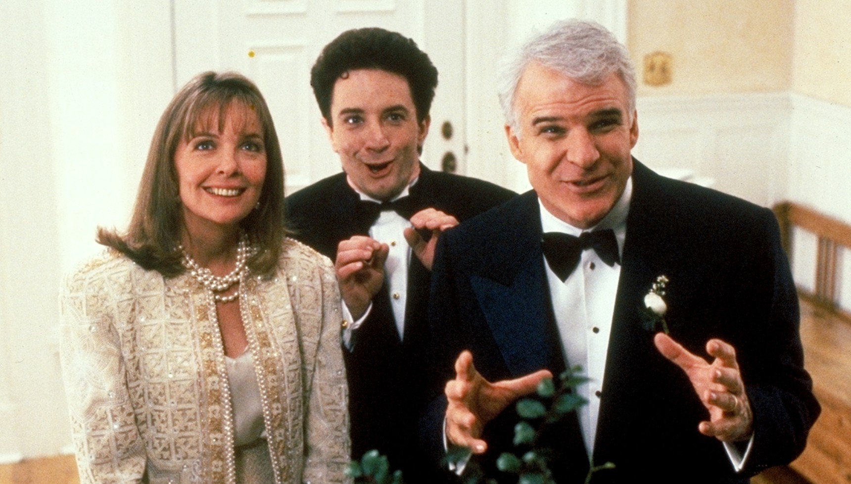Diane Keatin smiling next to Martin Short and Steve Martin in tuxedos in Father of the Bride