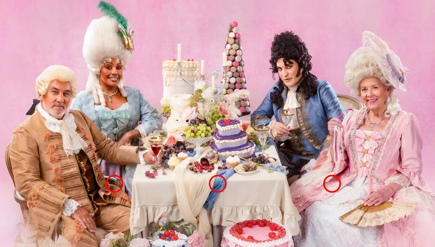 Paul Hollywood, Alison Hammond, Noel Fielding, and Prue Leith sitting at a table with cakes as they wear extravagant clothes