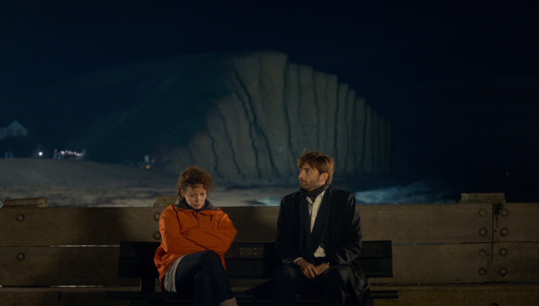 Olivia Colman and David Tennant sitting on a bench on the Broadchurch pier
