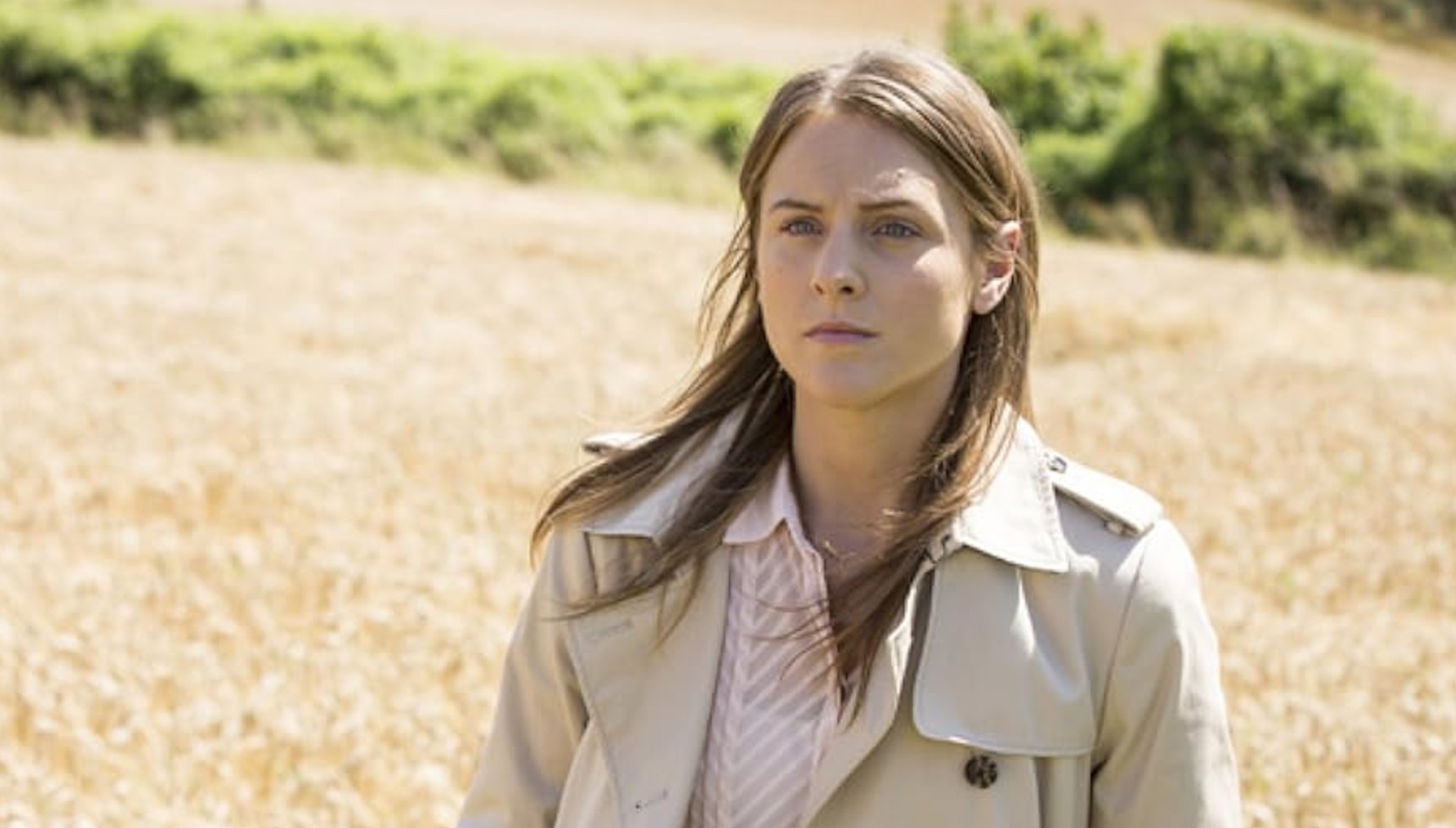 kelly Gough in a beige trench coat in a wheat field in Broadchurch