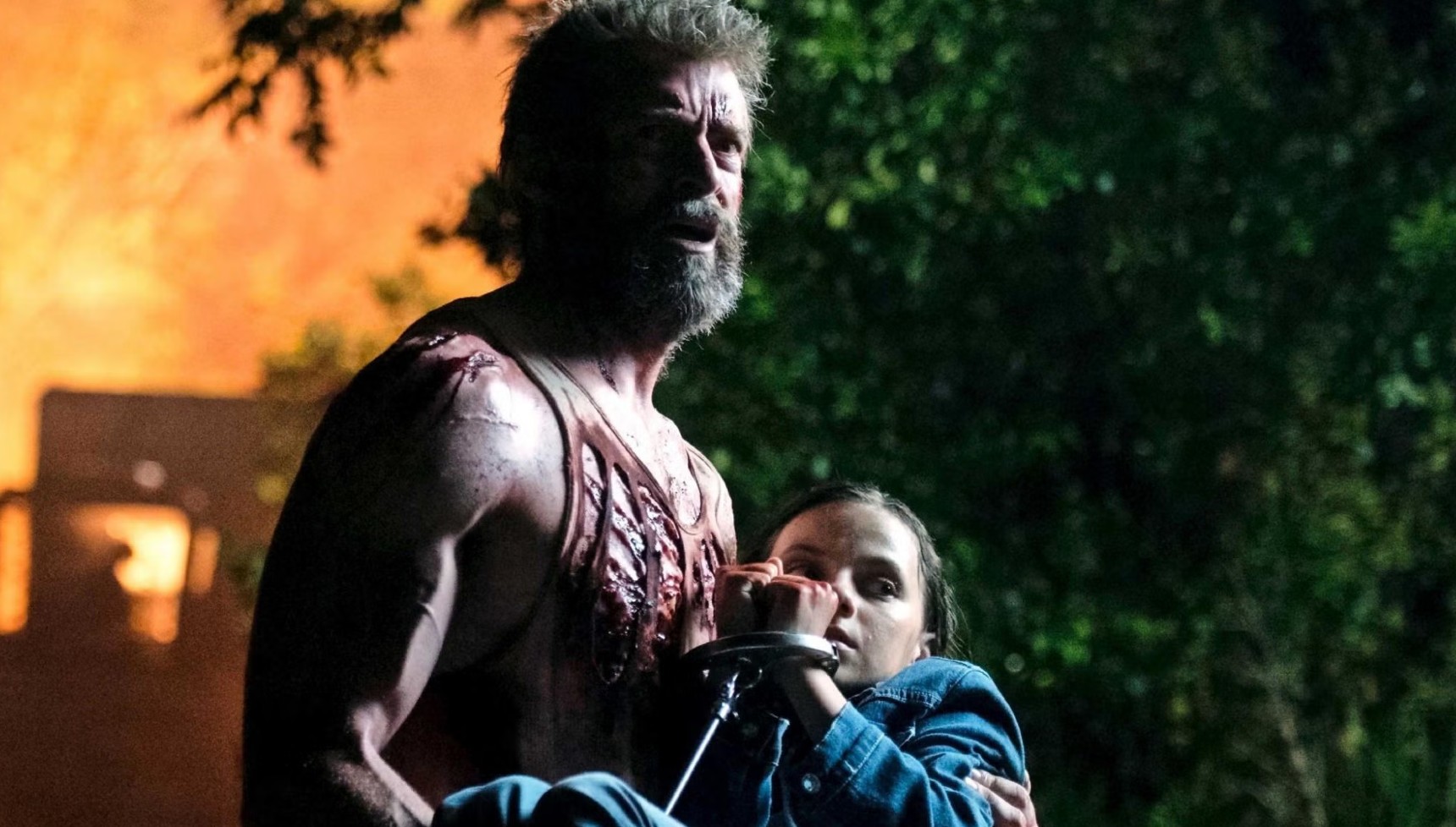 Hugh Jackman's Logan with a grey beard holding Daphne Keen in Logan