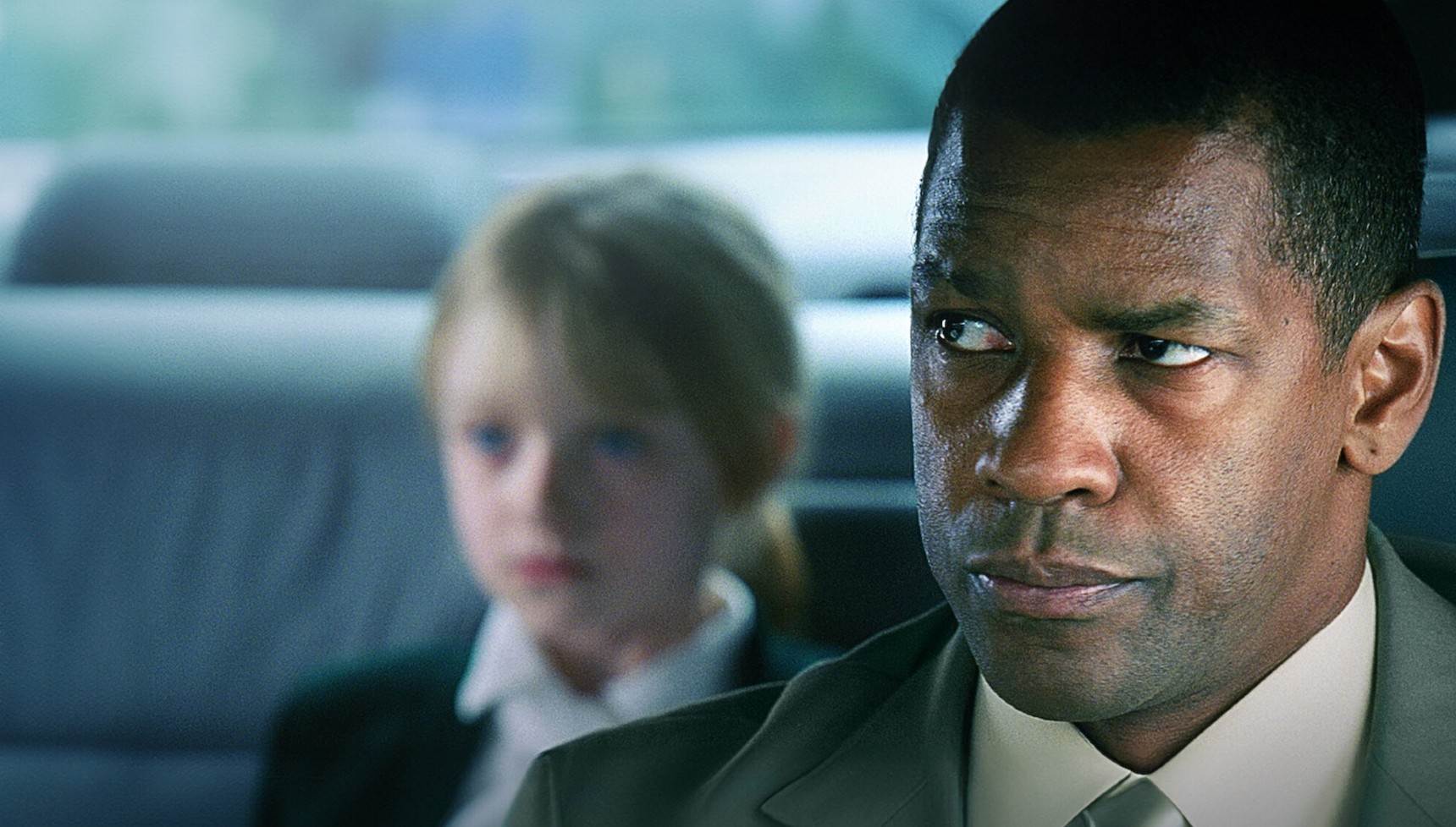 Denzel Washington sitting in the car with Dakota Fanning behind him in Man on Fire
