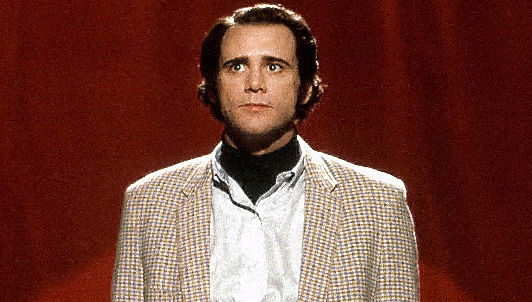 Jim Carrey dressed as Andy Kaufman in front of a red curtain in Man on the Moon