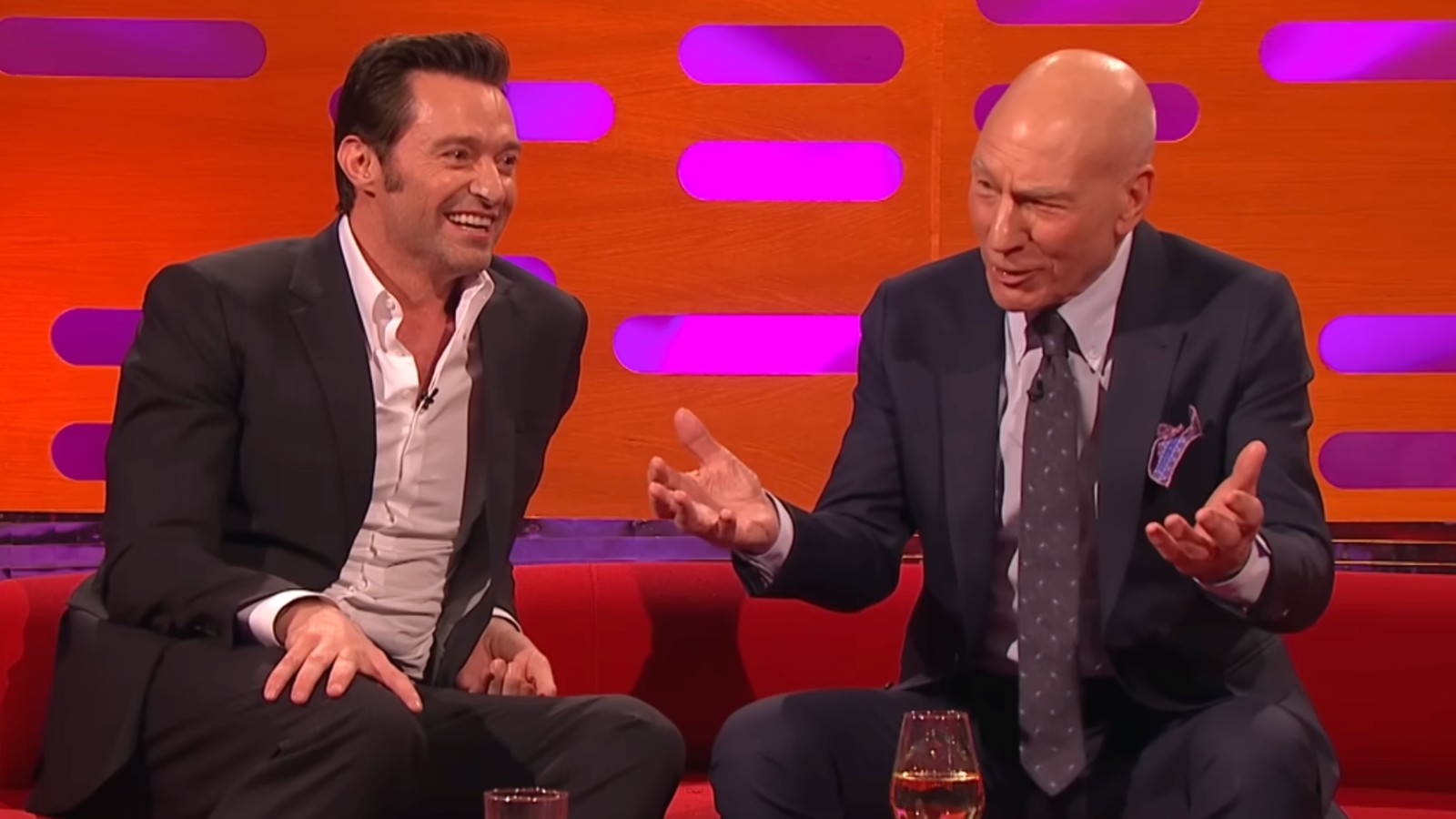 Hugh Jackman smiling as Patrick Stewart holds up his hands on The Graham Norton Show
