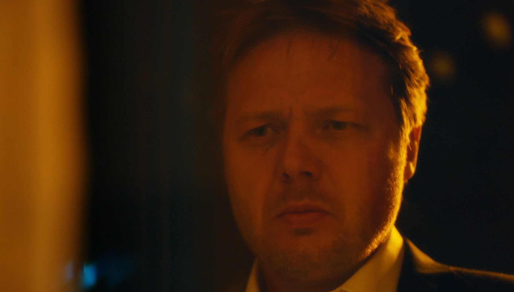 Shaun Dooley standing outside a window at night