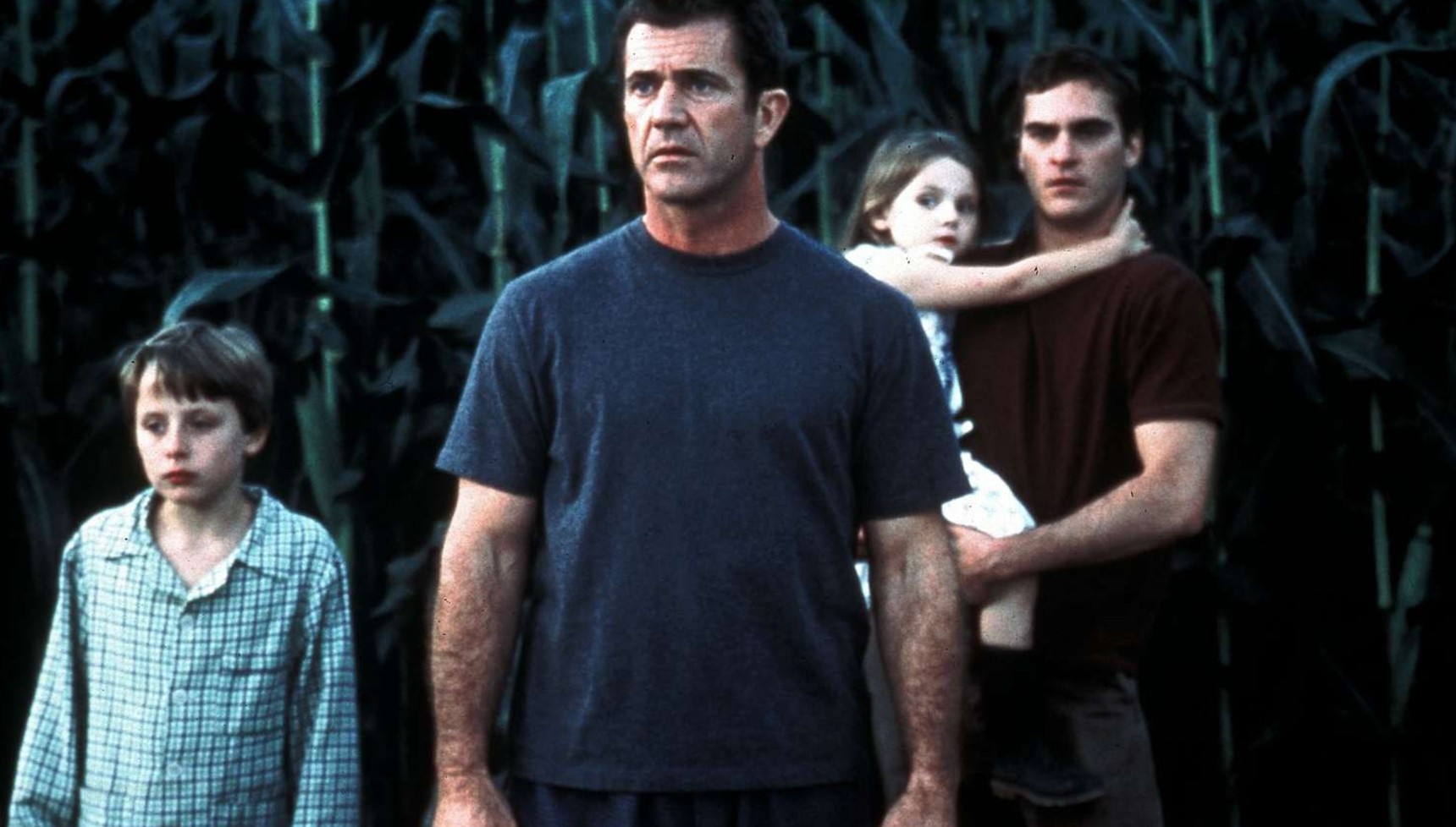 Mel Gibson, Joaquin Phoenix, and two kids standing in front of Crops in Signs