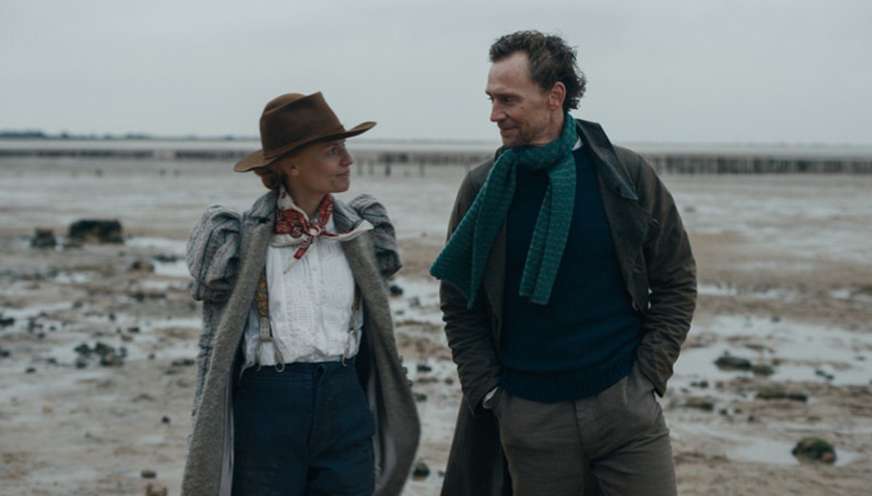 Woman and a man looking at each other whilst strolling along a beach