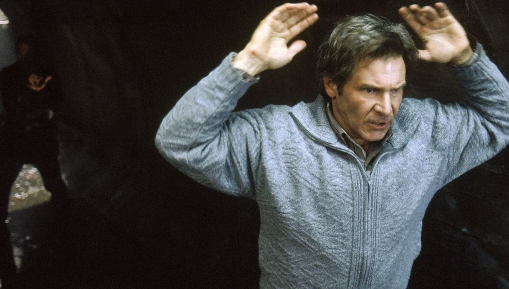 Tommy Lee Jones pointing a gun at Harrison Ford with his arms in the air in The Fugitive