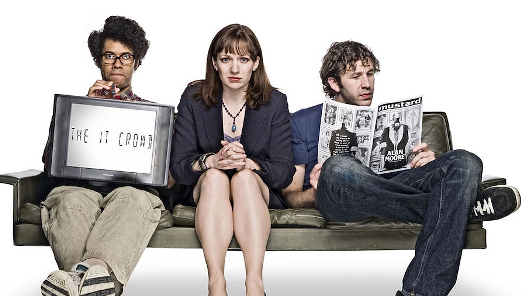 Moss, Jen, and Roy from The It Crowd sitting on a couch together as Moss holds a TV and Ross reads a comic