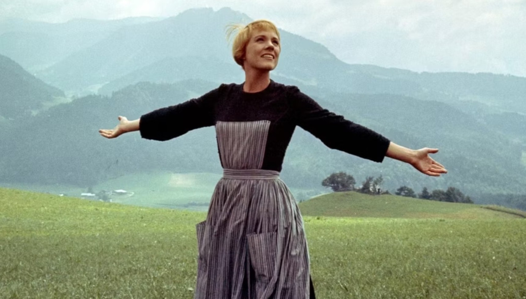 Julie Andrews with her arms out wide singing the first song in The Sound of Music
