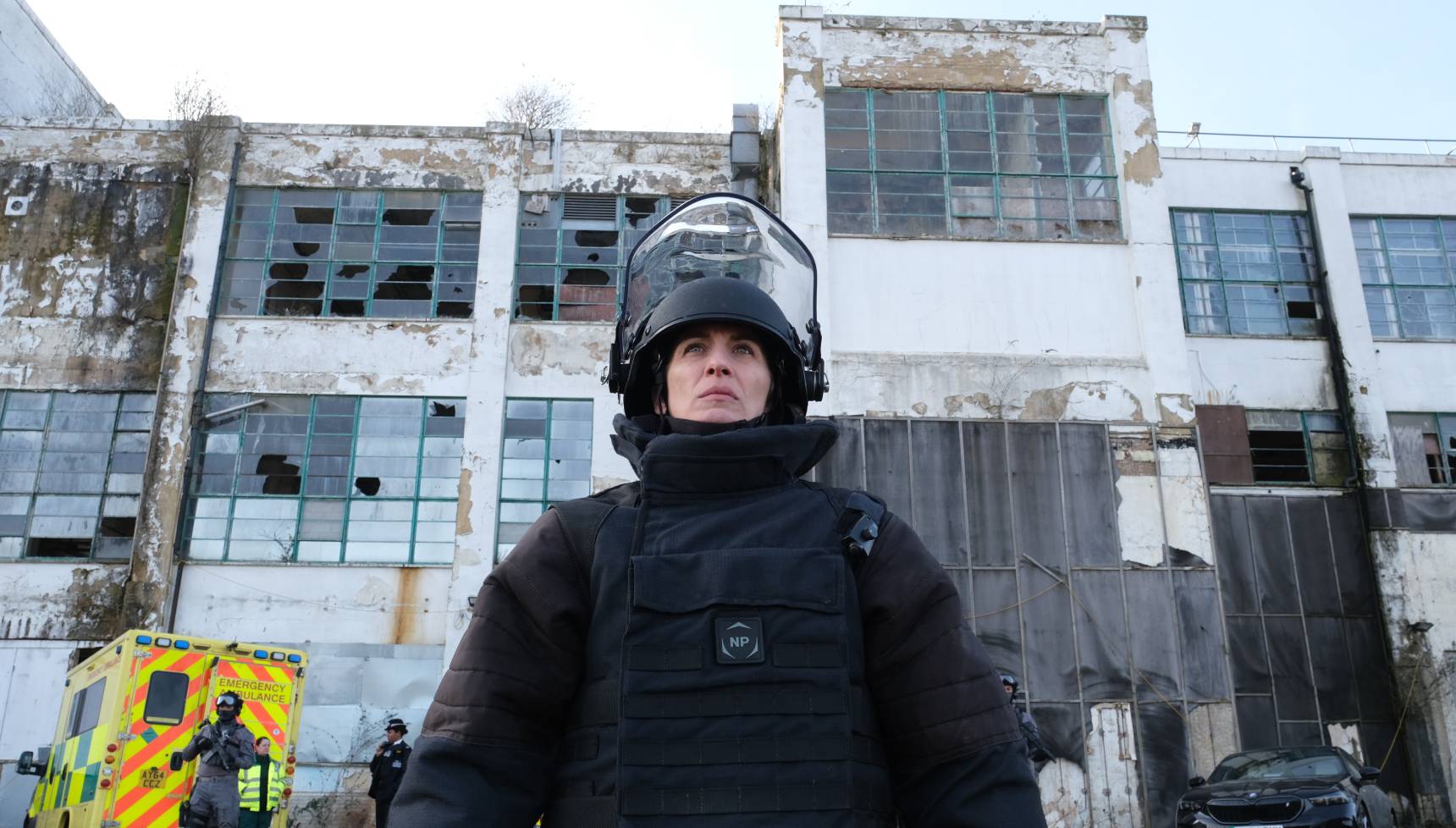 Lana Washinton stands in her kit in Trigger Point series 3 with a disused factory behind her