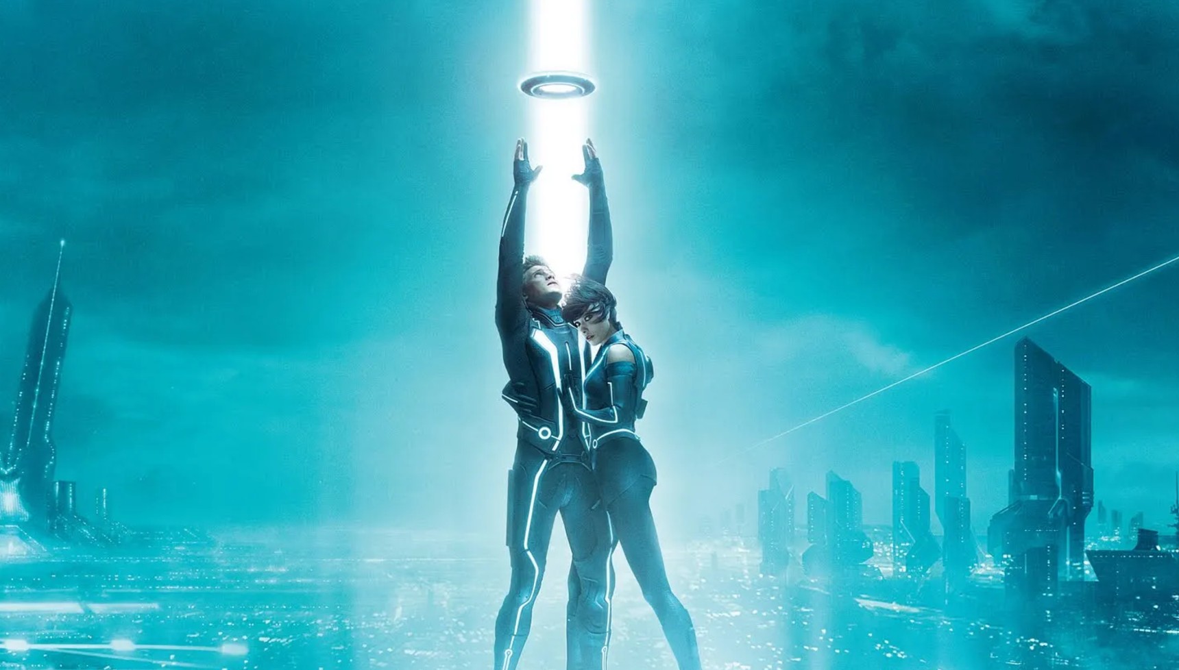 Garrett Hedlund reaching for a disc next to Olivia Wilde against a blue neon backdrop in Tron: Legacy
