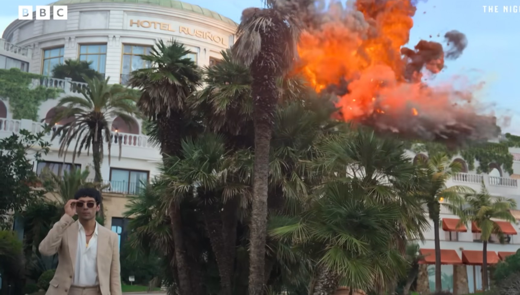 Diego Calva's Teddy walking away from an explosion in The Night Manager