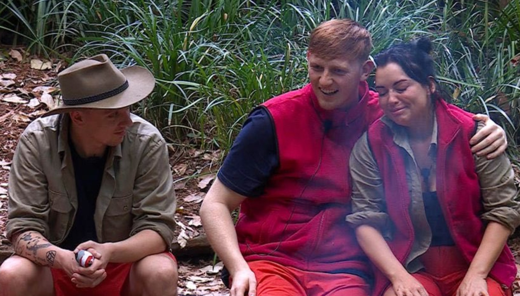 Aitch smiling at Ginge hugging Shona in I'm A Celebrity