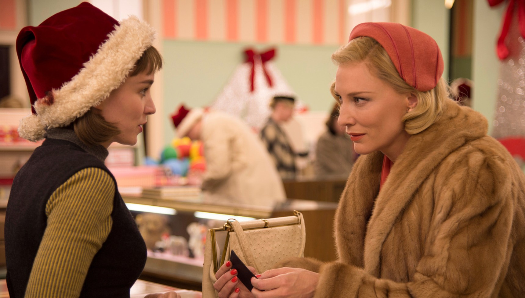 Rooney Mara wearing a Santa hat talking to Cate Blanchett