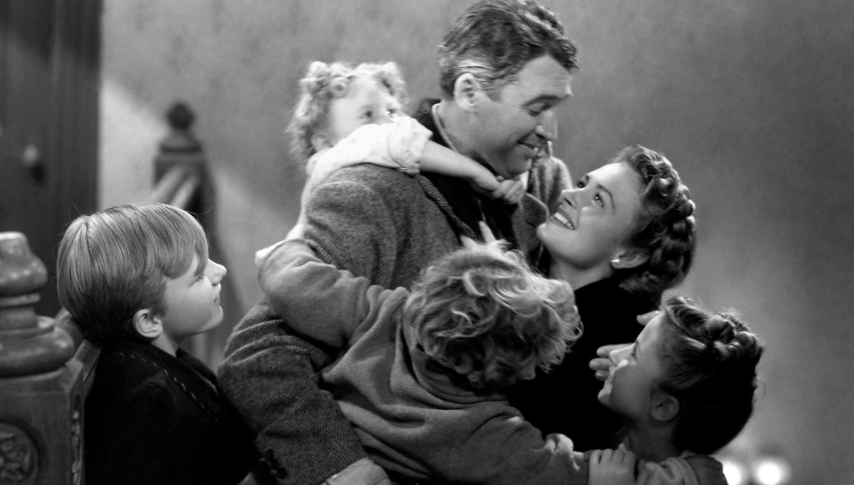 George Bailey smiling and surrounded by his family in It's a Wonderful Life
