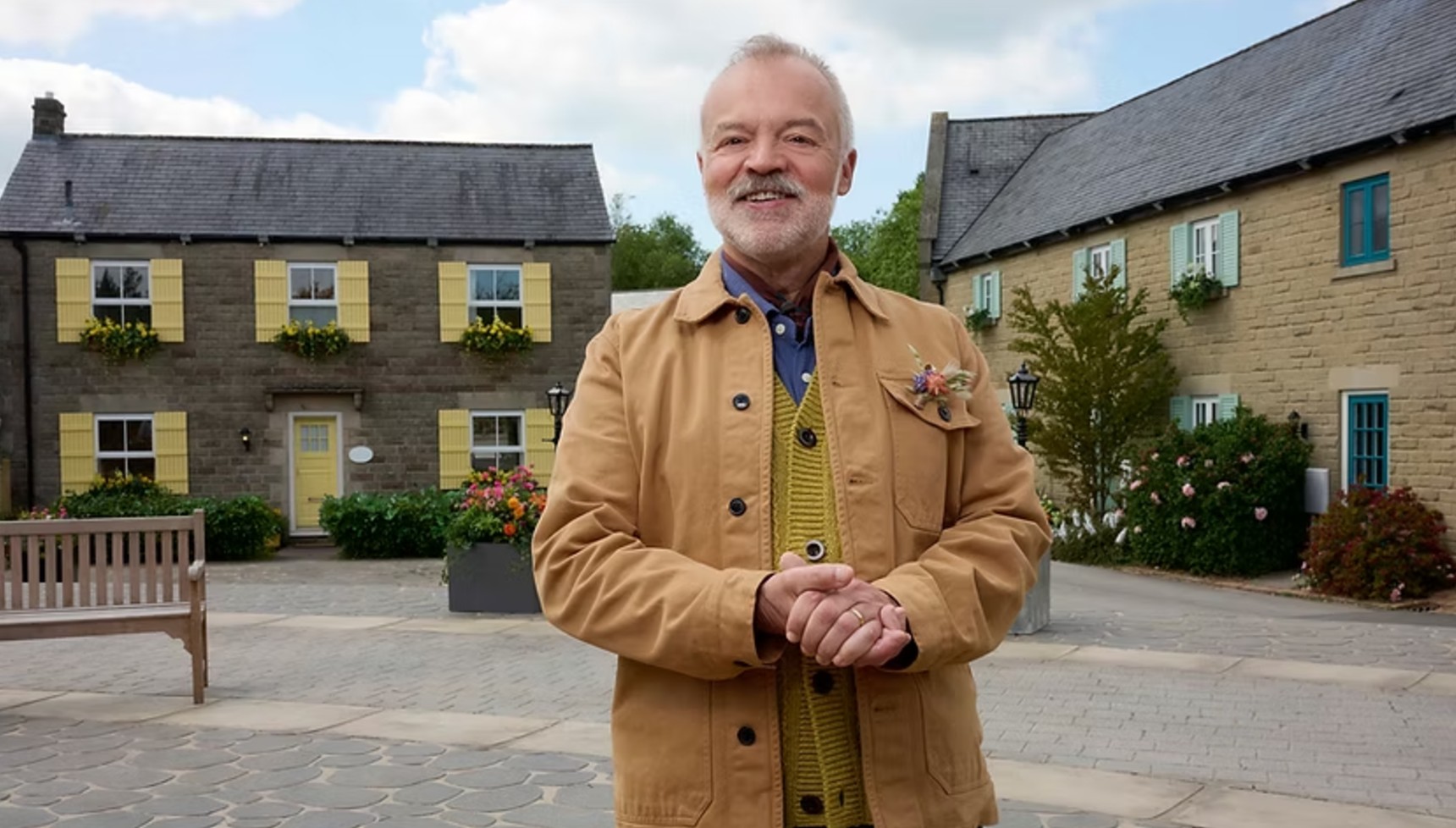 Graham Norton standing in front of houses on the set of The Neighbourhood