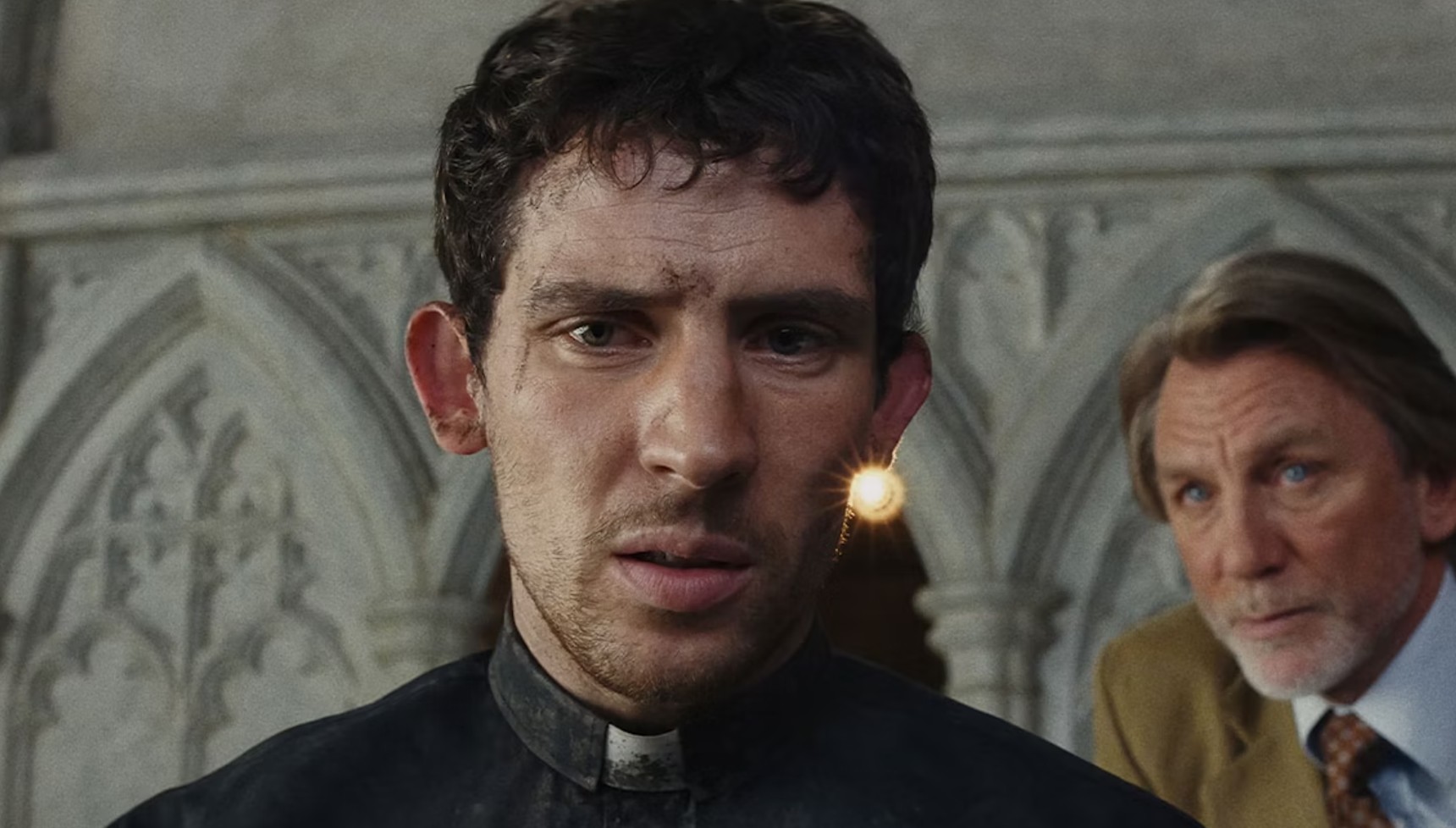 Josh O'Connor as Jud with Daniel Craig's Benoit Blanc peering behind him