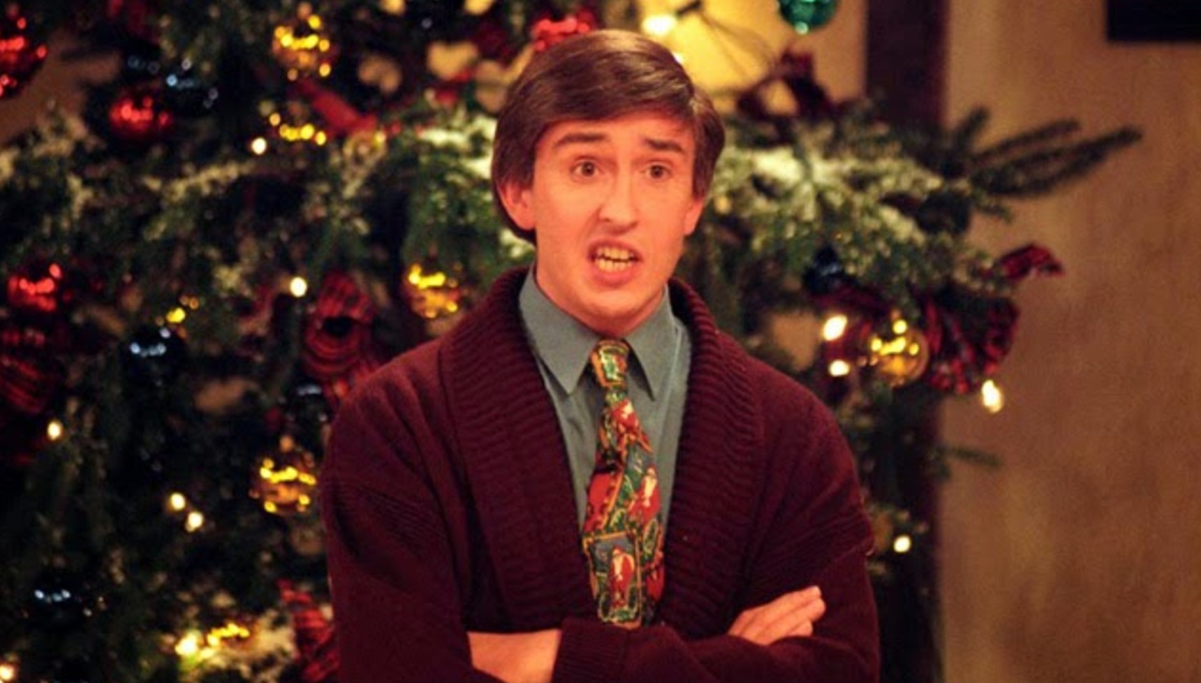 Alan Partridge standing in front of a Christmas tree in Knowing Me, Knowing Yule