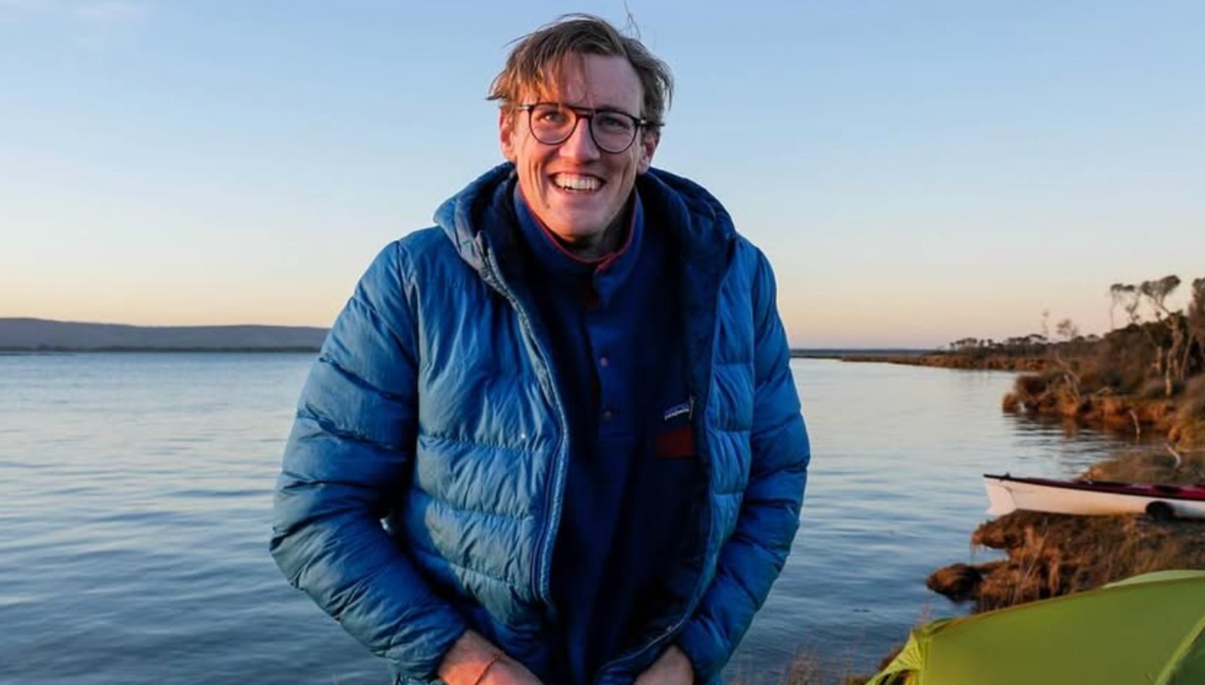 Mack Horton in a blue jacket next to the water