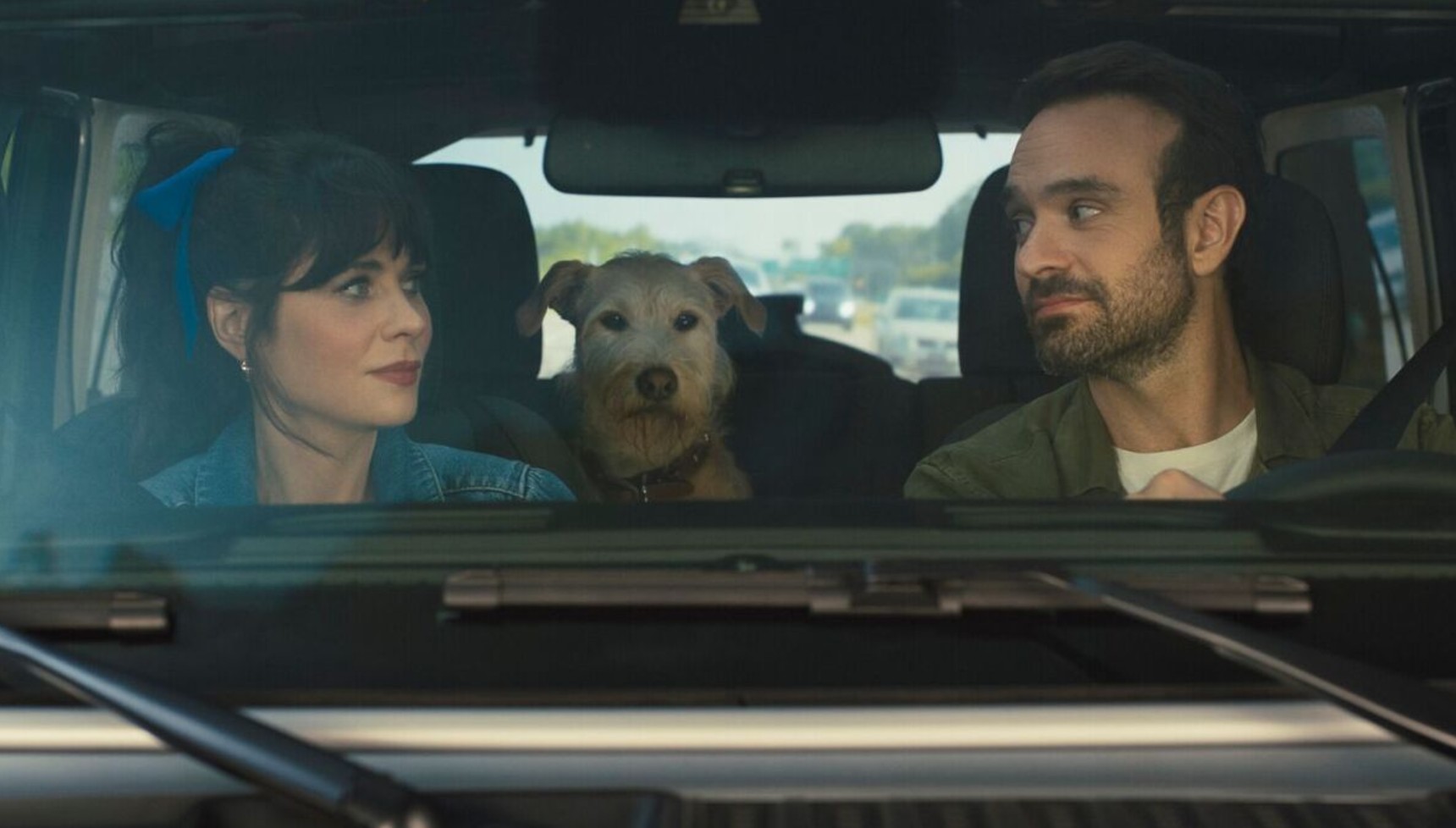 Zooey Deschanel and Charlie Cox sitting in a car with a dog between them