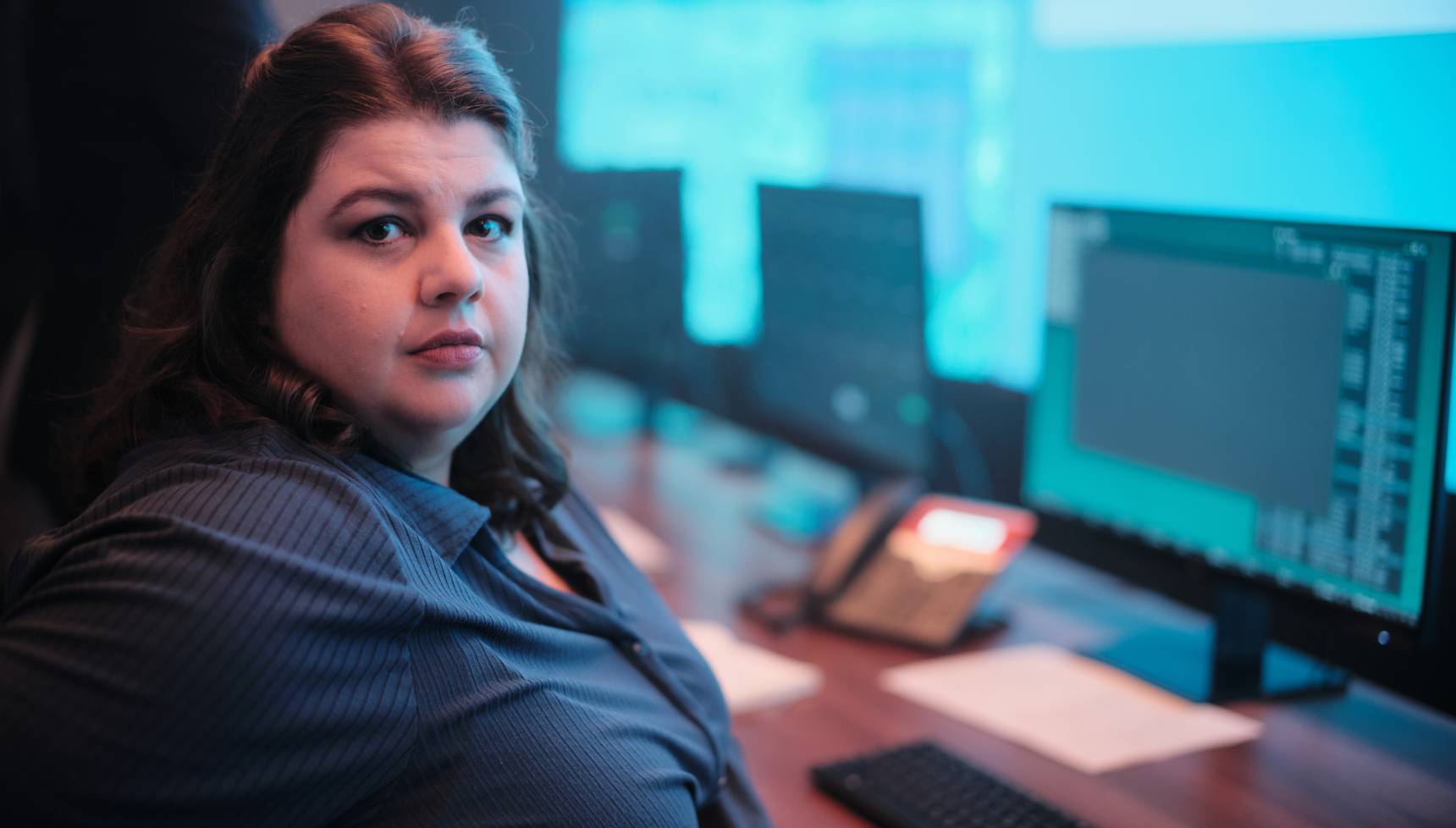 Close up of Megan Campbell at her desk in Red Eye season 2
